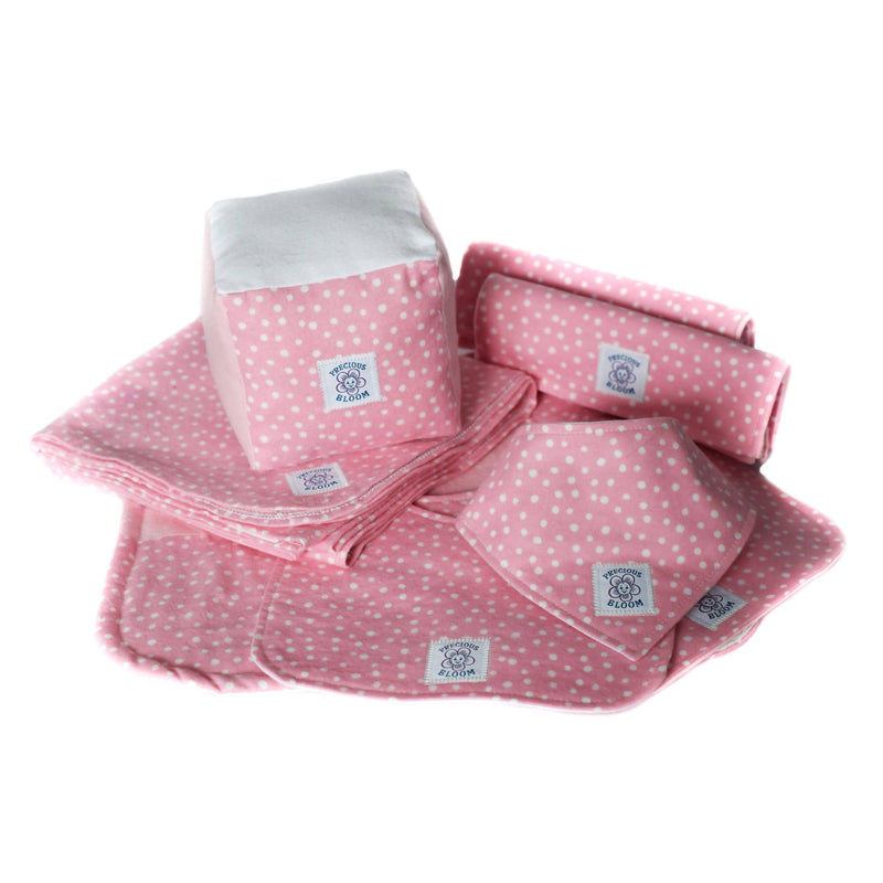 So Soft Organic Baby Accessories Gift Package shown open on a table, including a receiving blanket, a change pad, 2 burp pads, 3 sizes of bibs, and a play/learning block.